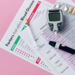 Glucometer, syringe, and health charts for diabetes management on pink background.